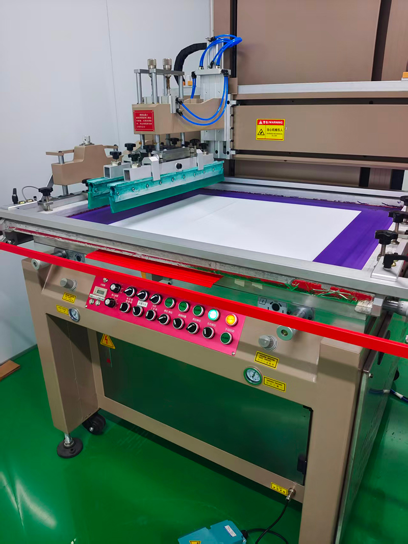 Semi-automatic silk screen printer printing purple solder mask onto a white PCB panel with the squeegee mid-stroke